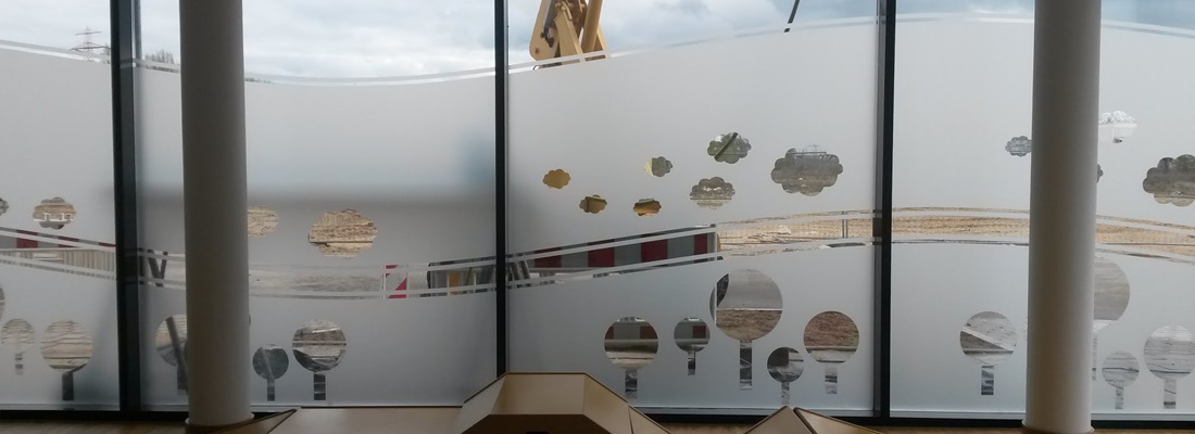 Fensterfront mit satinierten Sichtschutzfolien im Wellenmuster und ausgestanzten Baum-Motiven