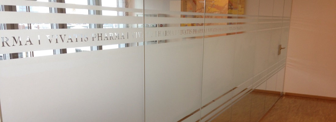 Glastrennwand mit satinierter Sichtschutzfolie, integriertem Logo-Schriftzug und dekorativen Linien im Büro